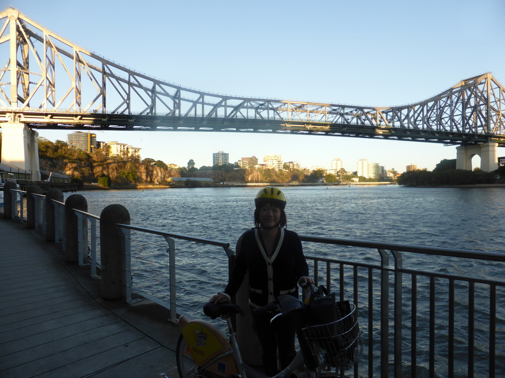 Miaomiao with her CityCycle bicycle at the City Reach Boardwalk, with a view on the Story Bridge over the Brisbane River