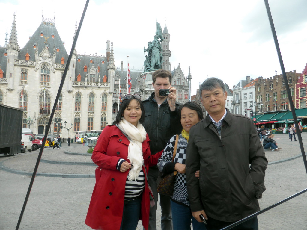 Tim, Miaomiao and Miaomiao`s parents, reflected in a mirror on the Markt square, with a view on the Provincial Court and the Statue of Jan Breydel and Pieter de Coninck