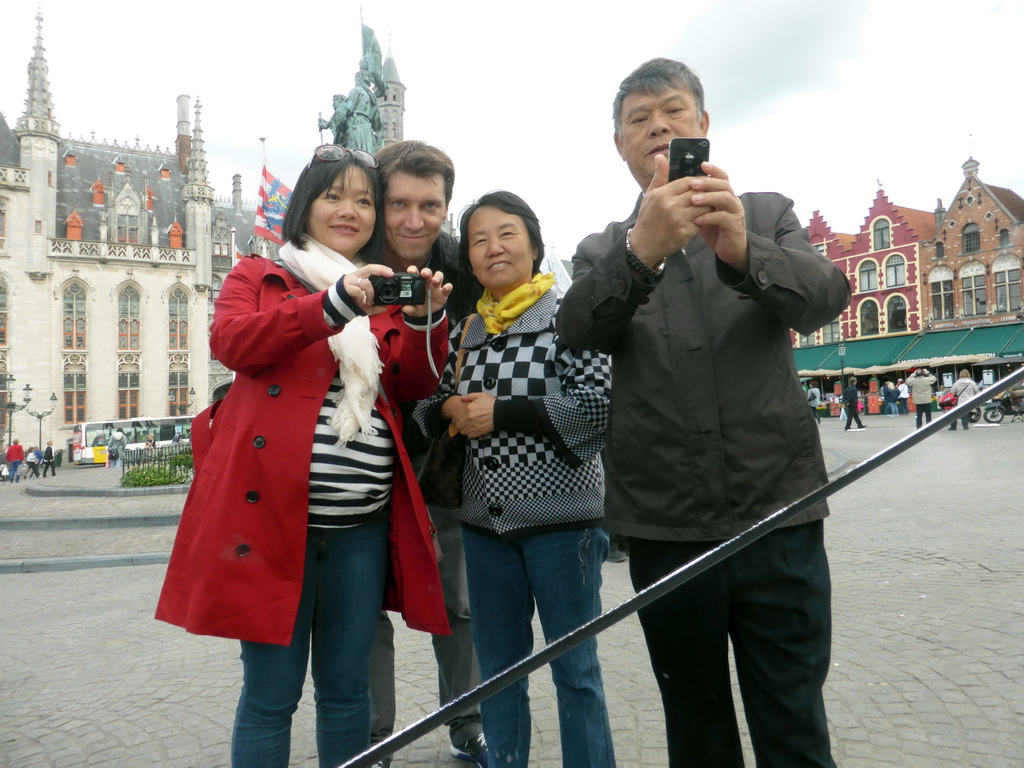 Tim, Miaomiao and Miaomiao`s parents, reflected in a mirror on the Markt square, with a view on the Provincial Court and the Statue of Jan Breydel and Pieter de Coninck