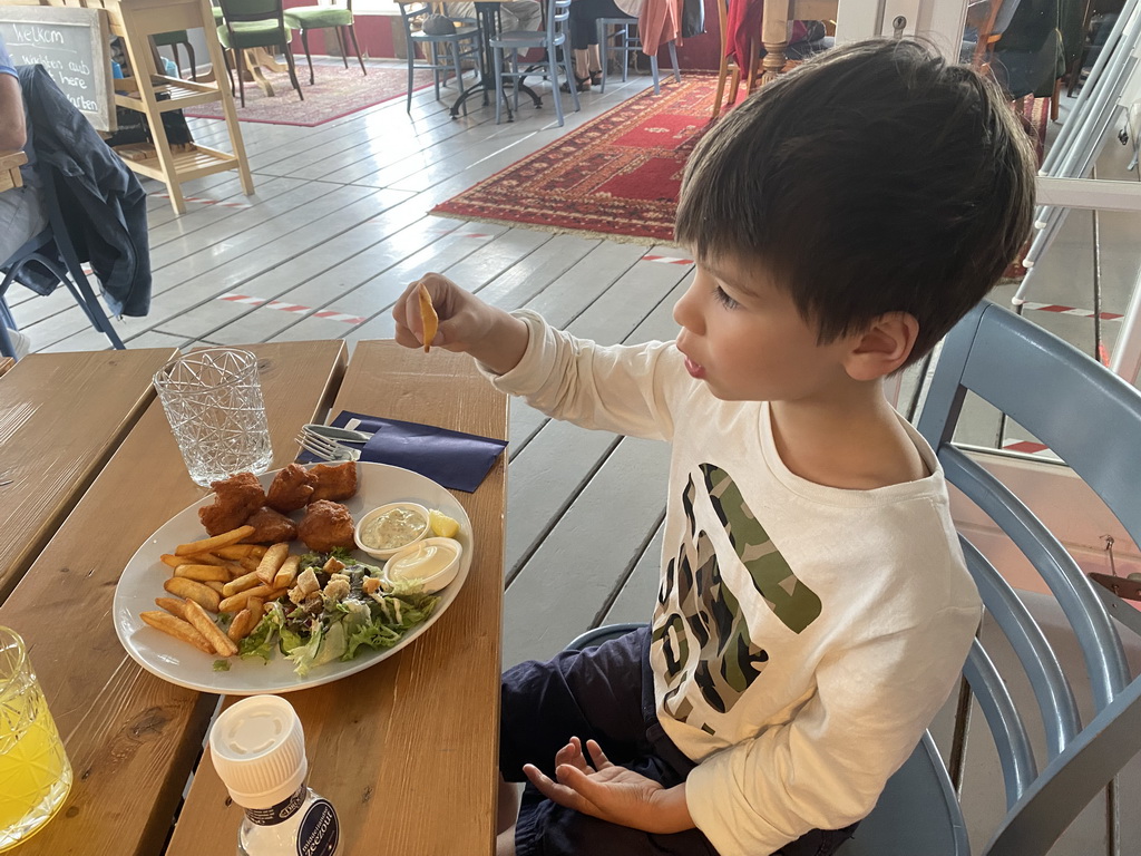 Max eating fried cod with fries and salad at the Bru 17 restaurant