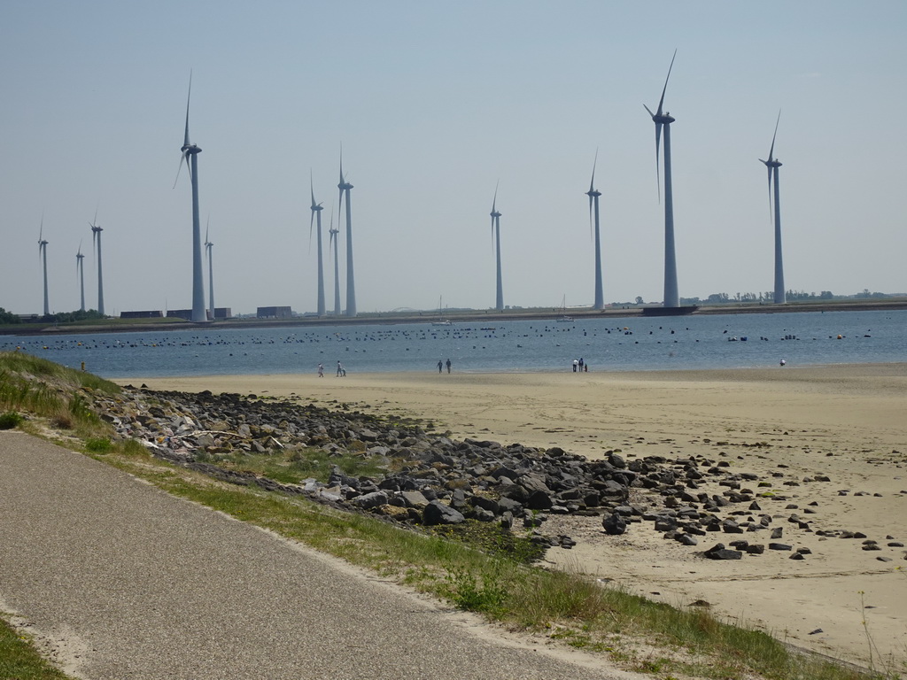 People looking for seashells at the beach at the south side of the Grevelingendam, the Krammer lake and windmills at the Krammersluizen sluices, viewed from the playground of Restaurant Grevelingen