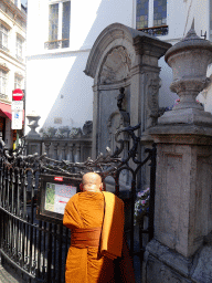 Buddhist monk in front of the fountain `Manneken Pis` at the crossing of the Rue de l`Étuve street and the Rue du Chêne street
