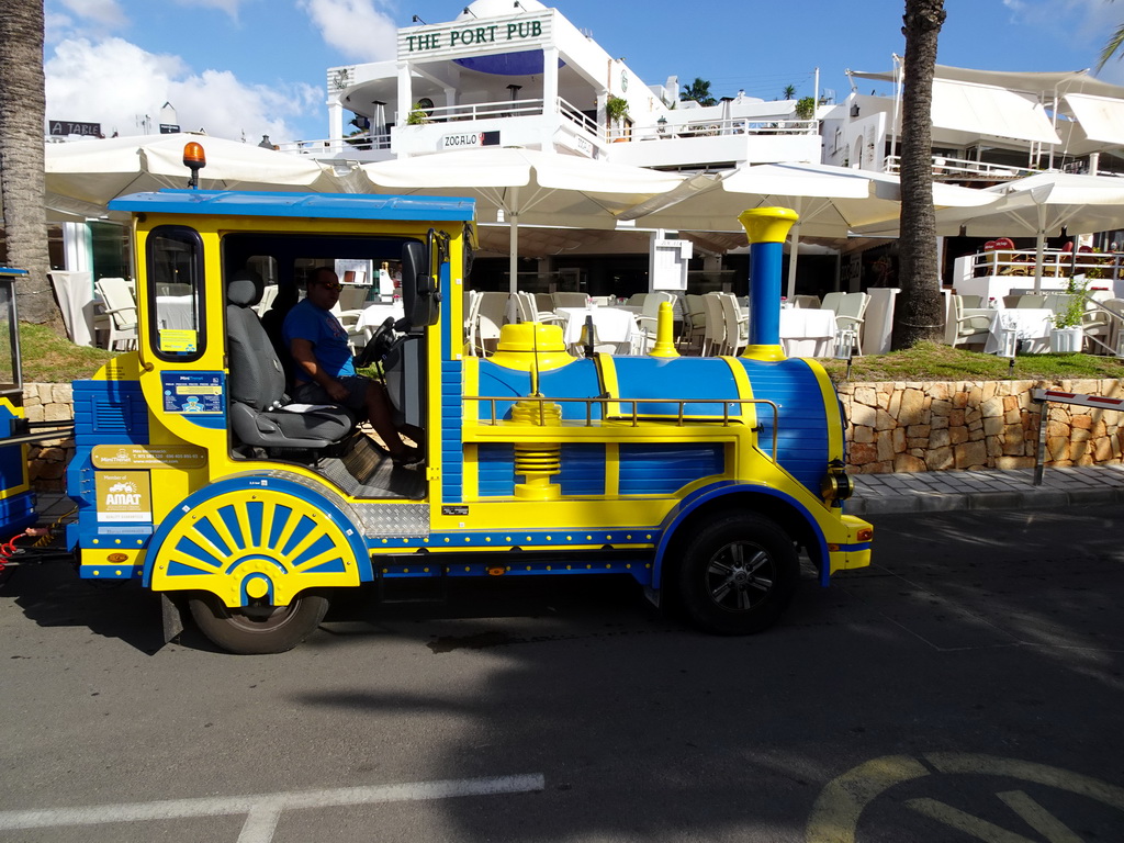 Tourist train at the Avinguda de Cala Llonga street and the east side of the Port Esportiu Marina de Cala d`Or harbour