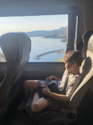 Max in the bus from the Grand Hotel Park to Dubrovnik Airport on the D8 road near the town of Plat, with a view on the pier at Beach Bucanj