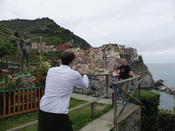 Tim with a statue at the Punta Bonfiglio hill, with a view on Manarola and its harbour