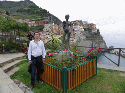 Tim with a statue at the Punta Bonfiglio hill, with a view on Manarola and its harbour