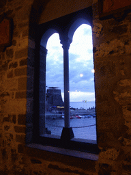 Window at the Chiesa di Santa Margherita d`Antiochia church at Vernazza, with a view on the harbour and the Doria Castle, at sunset