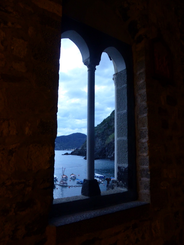 Window at the Chiesa di Santa Margherita d`Antiochia church at Vernazza, with a view on the harbour and Monterosso al Mare, at sunset