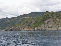 Manarola, its railway station and the Via dell`Amore path, viewed from the ferry to Riomaggiore
