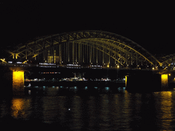 The Hohenzollernbrücke railway bridge over the Rhein river and the tower of the Groß St. Martin church, viewed from the Kennedy-Ufer street, by night