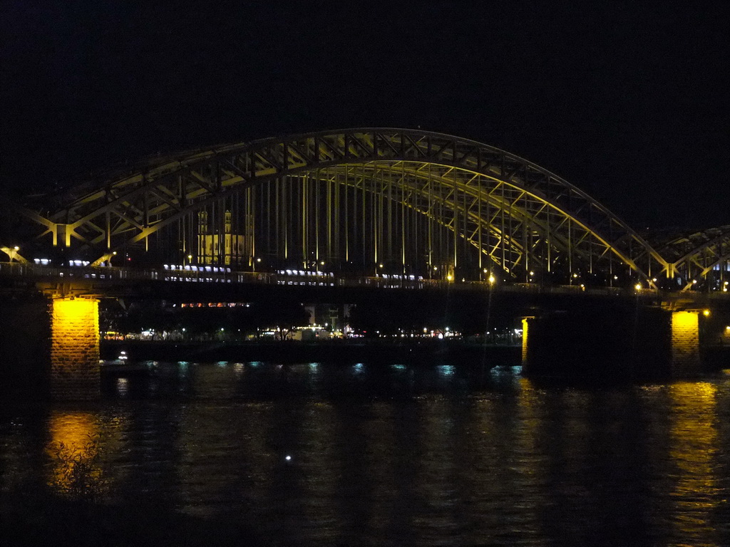 The Hohenzollernbrücke railway bridge over the Rhein river and the tower of the Groß St. Martin church, viewed from the Kennedy-Ufer street, by night