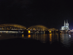 The Hohenzollernbrücke railway bridge over the Rhein river, the tower of the Groß St. Martin church and the Cologne Cathedral, viewed from the Kennedy-Ufer street, by night