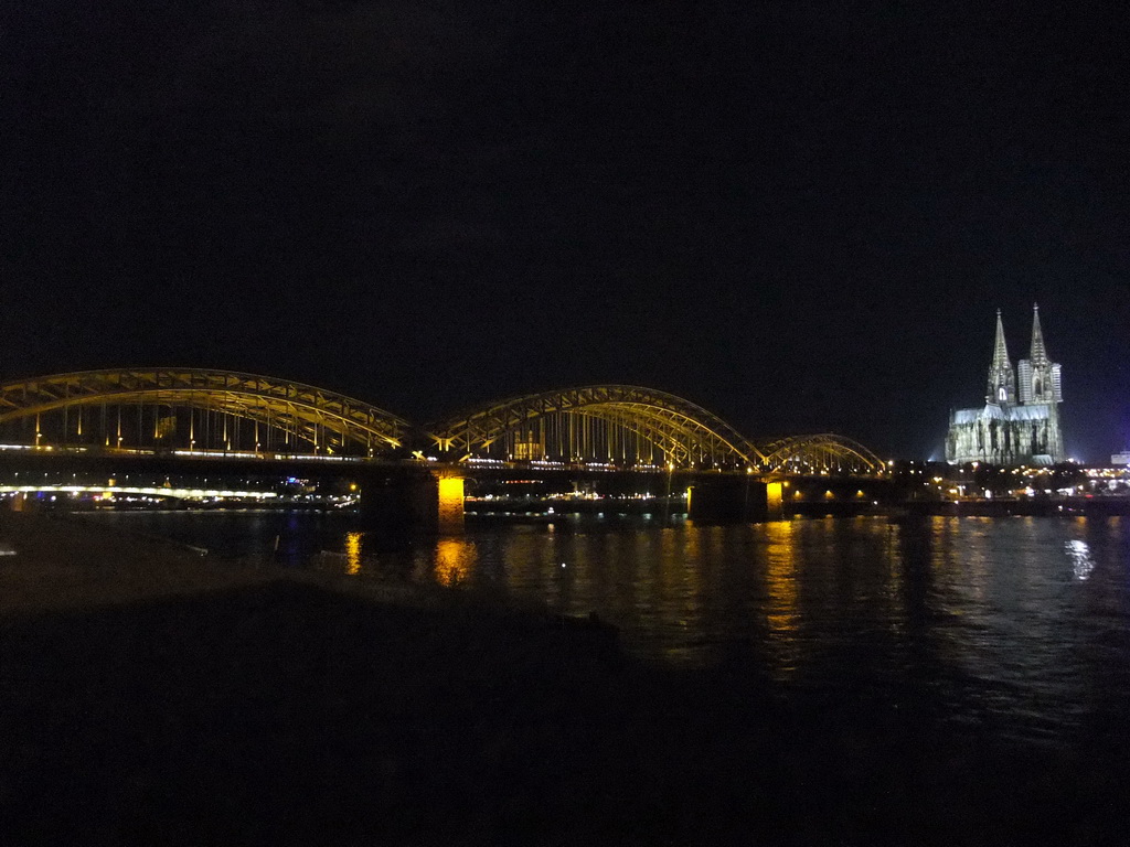 The Hohenzollernbrücke railway bridge over the Rhein river, the tower of the Groß St. Martin church and the Cologne Cathedral, viewed from the Kennedy-Ufer street, by night