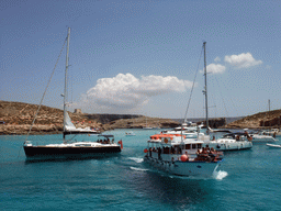 Boats at the Blue Lagoon, St. Mary`s Tower and Cominotto island, viewed from the Luzzu Cruises tour boat from Gozo to Comino
