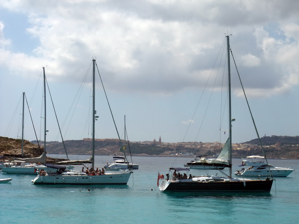 Boats at the Blue Lagoon, Cominotto island and the east coast of Gozo with the town of Ghajnsielem with the Ghajnsielem Parish Church, viewed from the Luzzu Cruises tour boat from Gozo to Comino