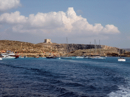 Boats at the Blue Lagoon and St. Mary`s Tower, viewed from the Luzzu Cruises tour boat from Comino to Malta