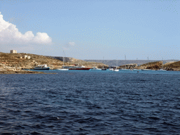 Boats at the Blue Lagoon, St. Mary`s Tower and Cominotto island, viewed from the Luzzu Cruises tour boat from Comino to Malta