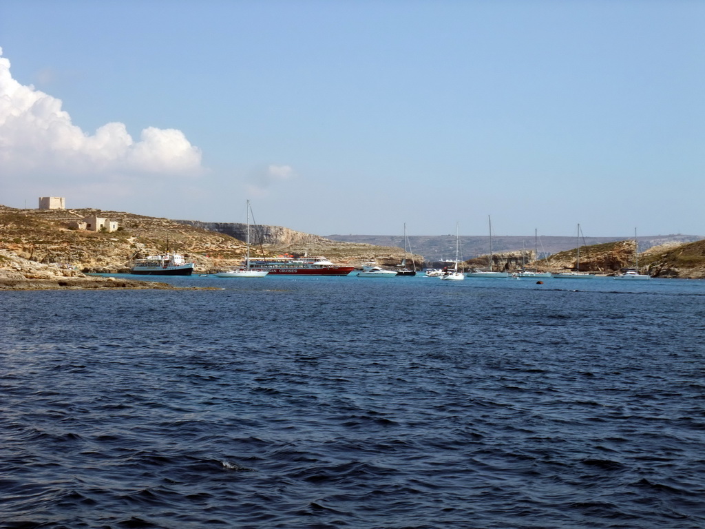 Boats at the Blue Lagoon, St. Mary`s Tower and Cominotto island, viewed from the Luzzu Cruises tour boat from Comino to Malta