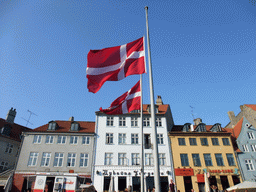 Danish flags, houses and restaurants at the north side of the Nyhavn harbour, viewed from the DFDS Canal Tours boat