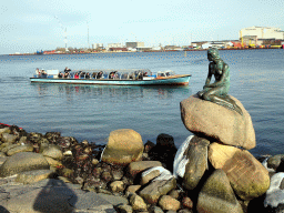 The statue `The Little Mermaid` at the Langelinie pier and a tour boat
