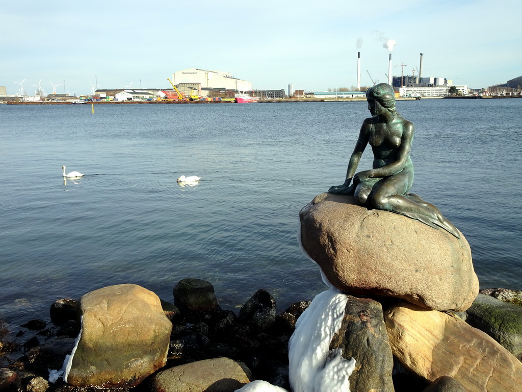 The statue `The Little Mermaid` at the Langelinie pier, with a view on the Amagerværket power station