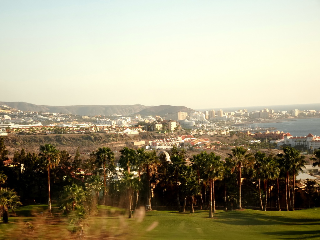 The Golf Costa Adeje golf course, palm trees and hotels in the town center, viewed from the rental car on the Calle Alcojora street