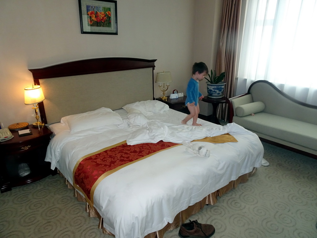 Max on the bed in our first bedroom at the New Sea View International Hotel