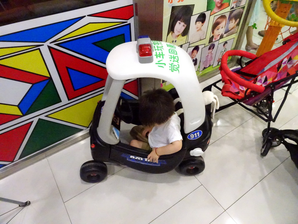 Max in a toy police car in a shopping mall at Fushun Street