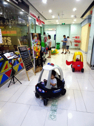 Miaomiao, Max and Miaomiao`s father in a toy police car in a shopping mall at Fushun Street