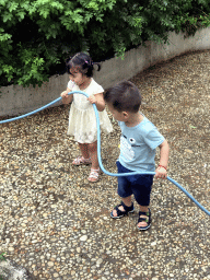 Max and his cousin with a garden hose at the square next to the photoshoot shop at Jinma Road