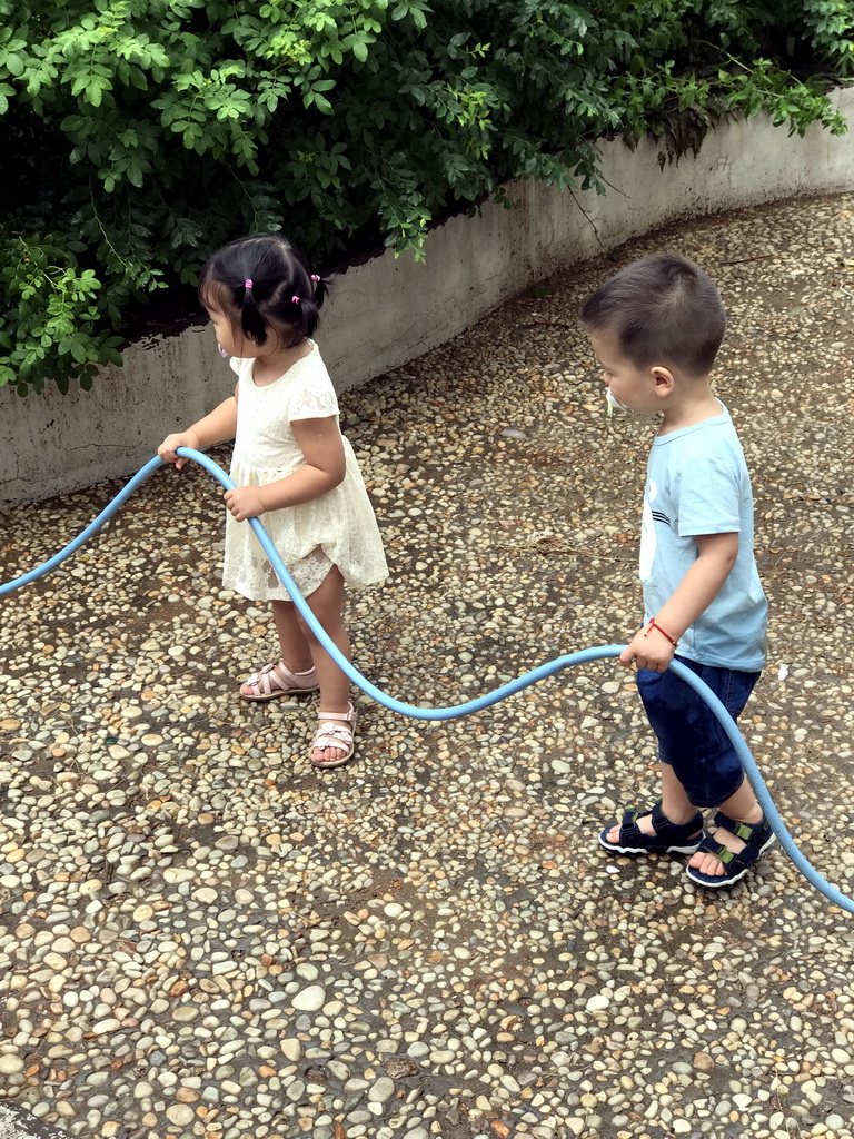 Max and his cousin with a garden hose at the square next to the photoshoot shop at Jinma Road