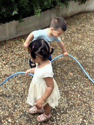 Max and his cousin with a garden hose at the square next to the photoshoot shop at Jinma Road