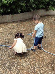 Max and his cousin with a garden hose at the square next to the photoshoot shop at Jinma Road