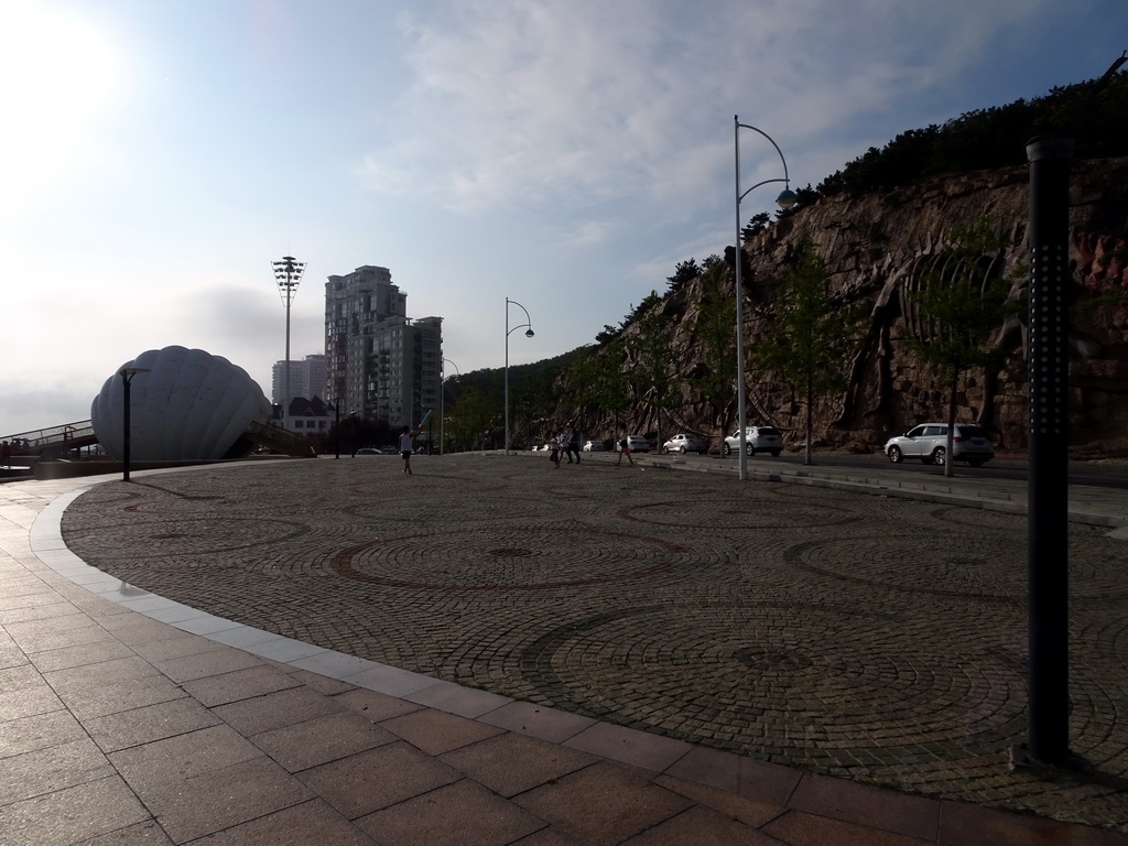 Square at Binhai Road with shell-shaped monument and rock with dinosaur skeletons