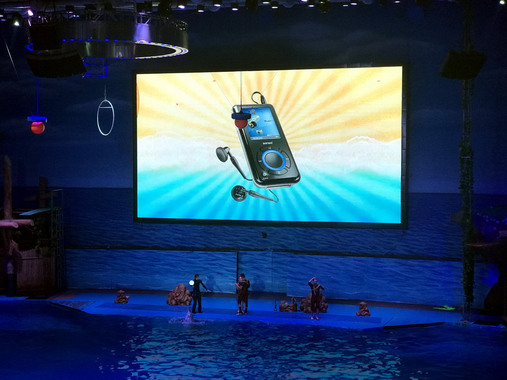 Dolphin and zookeepers in the Main Hall of the Pole Aquarium at the Dalian Laohutan Ocean Park, during the Water Show