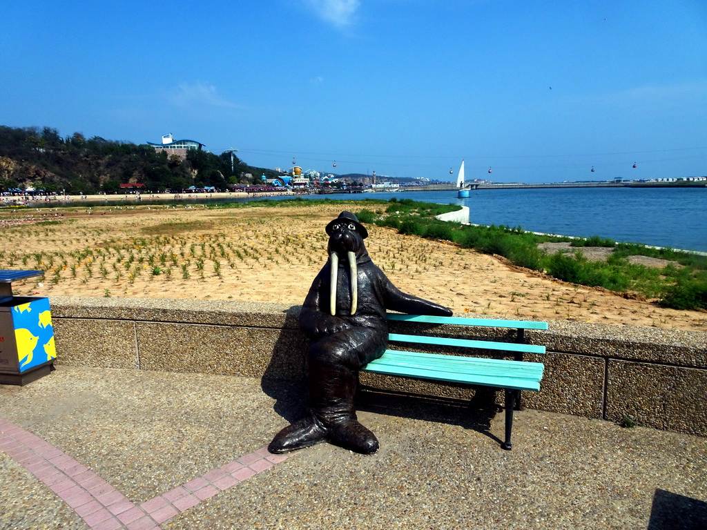 Walrus statue on a bench at the western side of the Dalian Laohutan Ocean Park, with a view on Laohu Beach Bay