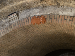 Statue of a bat in a tunnel at the Binnendieze canal, viewed from the tour boat