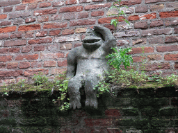 Statue of a monkey at a wall at the Binnendieze river, viewed from the tour boat