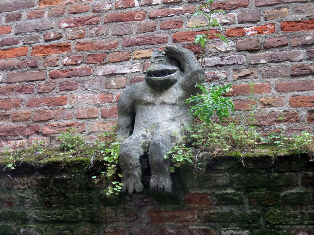 Statue of a monkey at a wall at the Binnendieze river, viewed from the tour boat