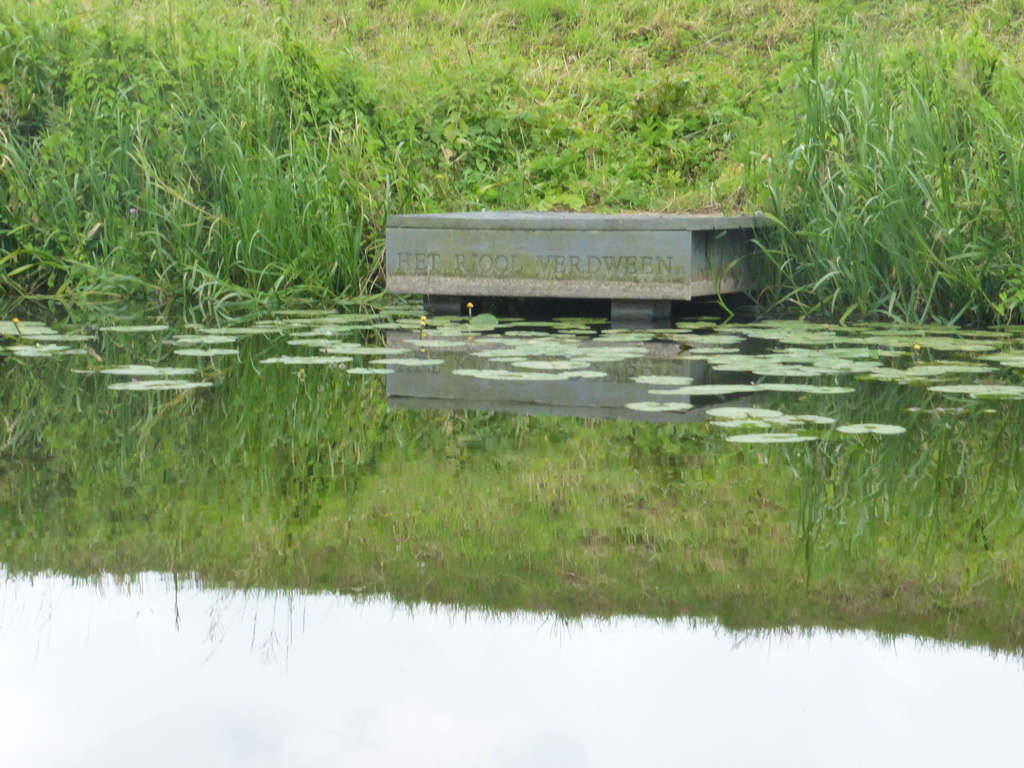 Small pier with the text `Het riool verdween` at the Singelgracht canal and the Bossche Broek grassland, viewed from the tour boat