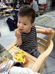 Max eating French fries at the McDonald`s restaurant at the Departure Hall of Schiphol Airport