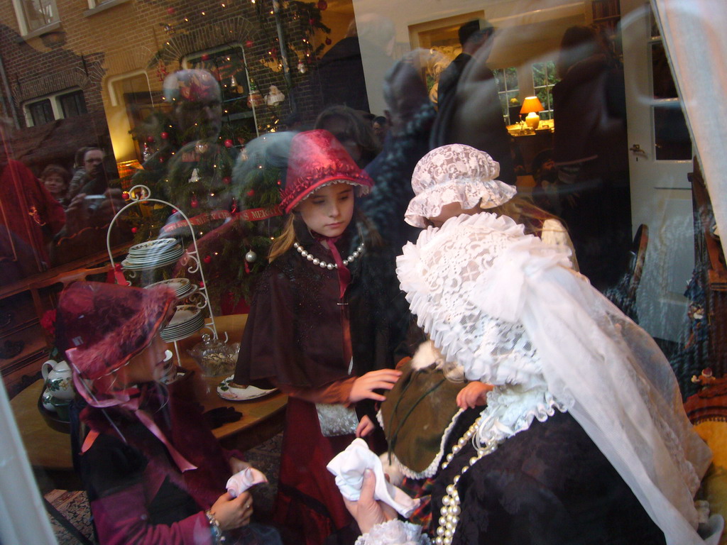 Actors in Victorian clothing in the window of a shop at the Walstraat street, during the Dickens Festival