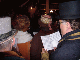 Actors in Victorian clothing singing at a square in the city center, during the Dickens Festival, at sunset