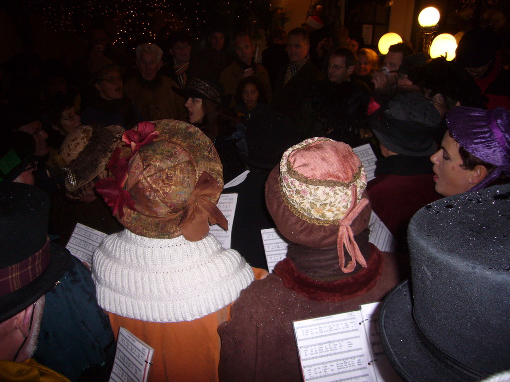 Actors in Victorian clothing singing at a square in the city center, during the Dickens Festival, at sunset