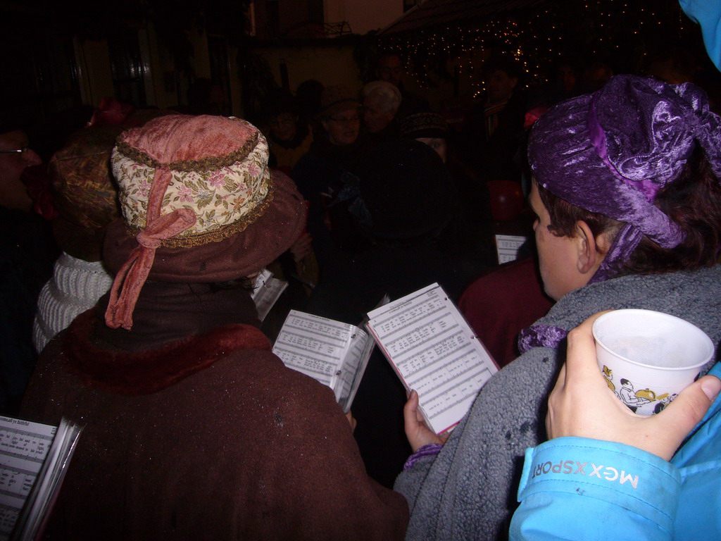 Actors in Victorian clothing singing at a square in the city center, during the Dickens Festival, at sunset