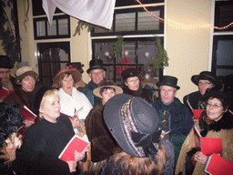 Actors in Victorian clothing singing at a square in the city center, during the Dickens Festival, at sunset