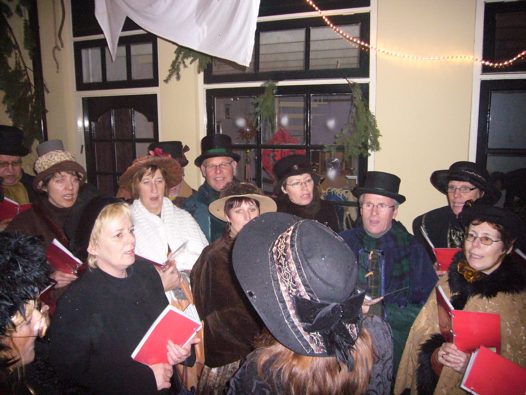 Actors in Victorian clothing singing at a square in the city center, during the Dickens Festival, at sunset