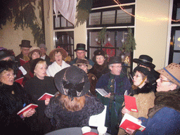 Actors in Victorian clothing singing at a square in the city center, during the Dickens Festival, at sunset