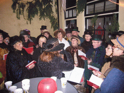 Actors in Victorian clothing singing at a square in the city center, during the Dickens Festival, at sunset