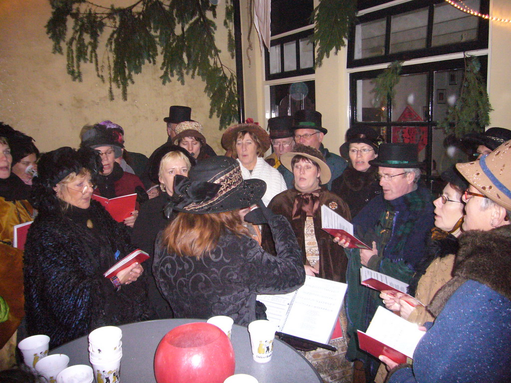 Actors in Victorian clothing singing at a square in the city center, during the Dickens Festival, at sunset